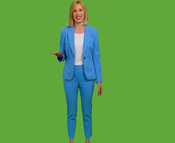 On-camera talent in a blue suit standing in front of the green-screen cyclorama in our Southington filming studio